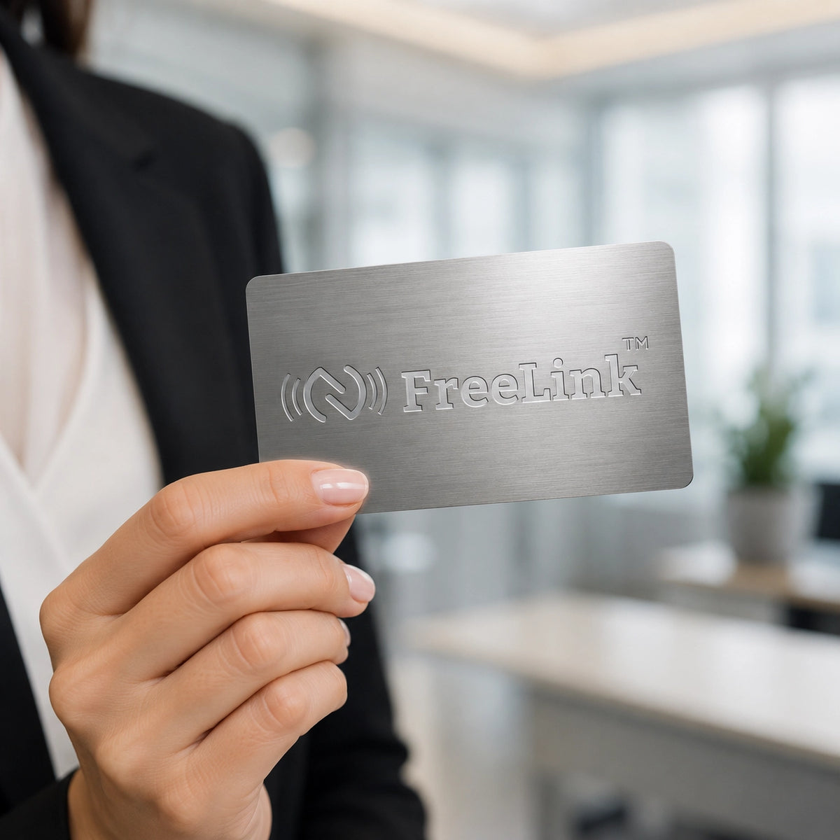 Premium Freelink Silver NFC Metal Business Card with laser-engraved FreeLink logo in a modern office workspace. Durable stainless steel NFC card for digital networking and smart business connections.